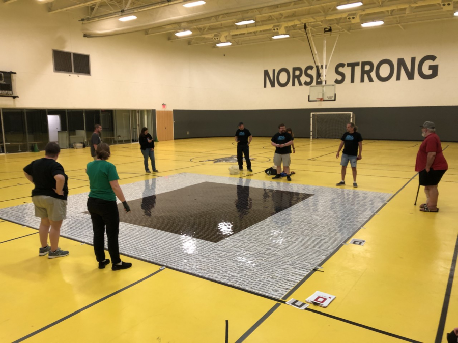 Sean Gardner, Shawn Reed, Paul Phillipy and others stand in a circle and create a massive 0 out of plastic gift cards at the NKU Campus Rec Center.