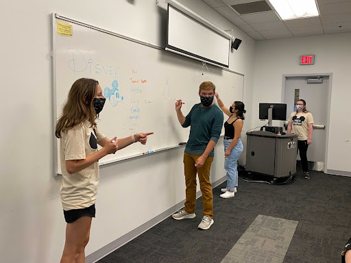 Co-presidents Allison Detmer, Shelby Lillie and general members Ben Lambert and Rachel Rivera drawing on the white board during a meeting. 
