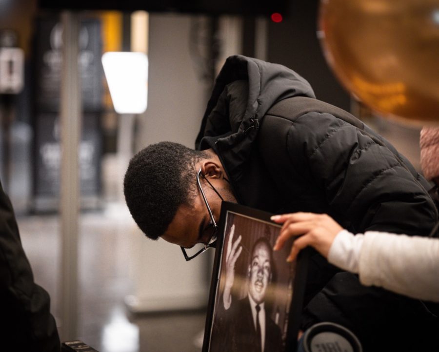 A participant in the MLK Candlelight Vigil looks down as a picture of Dr. Martin Luther King Jr. is held.