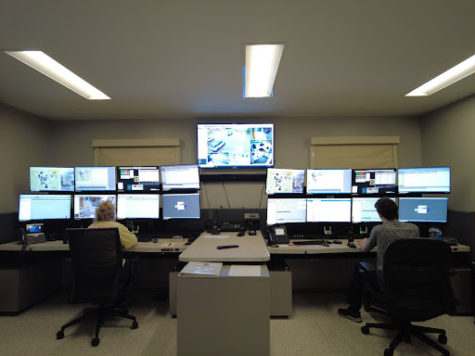 Dispatch workers look upon a wall of monitors as they take incoming calls and communicate with officers. 