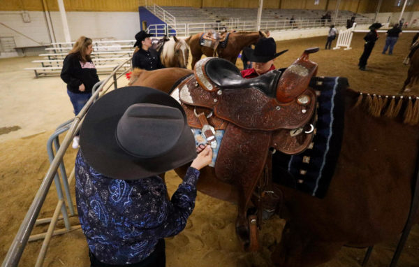Aj Allen, a senior at NKU, pins their number onto the saddle before competing. 