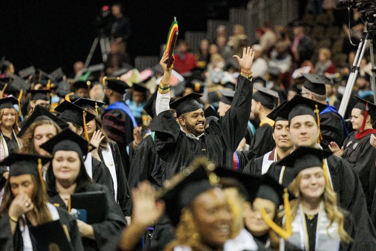 Graduates raise their hands in celebration following Saturdays fall commencement.