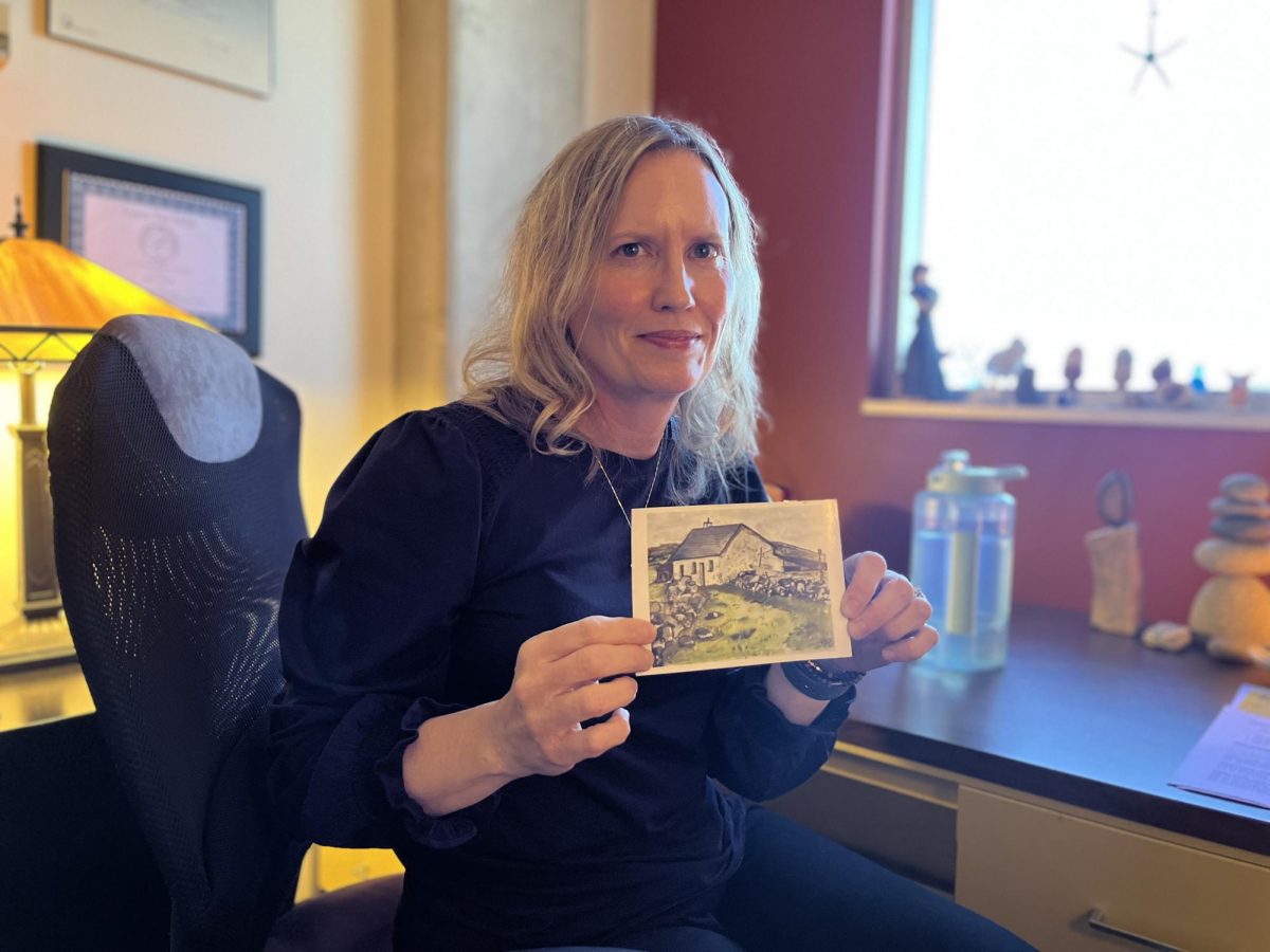 Moffett holding up just one of the many pieces of artwork and illustrations housed in her office in Landrum Hall.