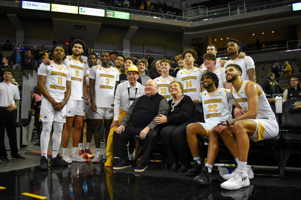 Former NKU mens basketball head coach Ken Shield and his wife Marie pose with the current mens basketball team at Saturday nights game.
