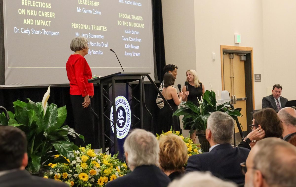 James Votruba's wife, Rachel Votruba (left), looks on as NKU School of the Arts students lead the singing of "Happy Birthday" to the former president.