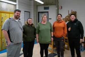 A group of custodians pause in their cleaning efforts to take a group photo.